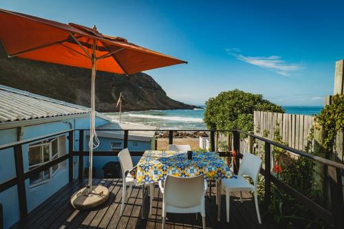 a table and chairs on a balcony with a view of the ocean at Silver Spray Beach Accommodation in Victoria Bay