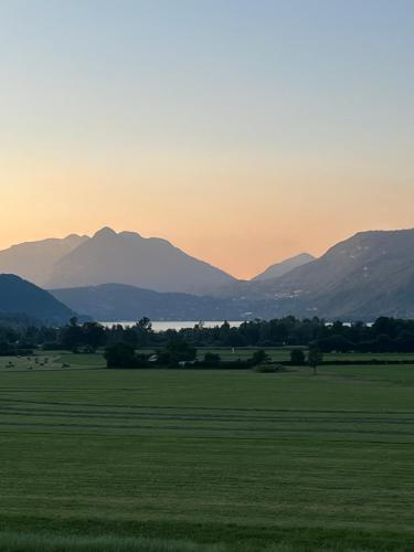 un coucher de soleil sur un champ avec des montagnes en arrière-plan dans l'établissement Superbe T3 A DOUSSARD, à Doussard