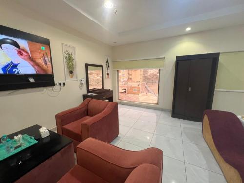 a living room with two chairs and a flat screen tv at Al Majaridah Hotel in Al Majaridah