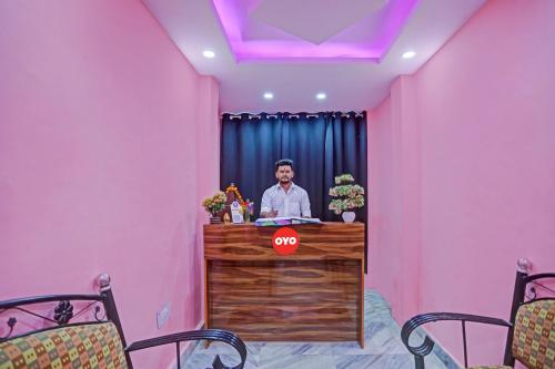 a man standing at a desk in a pink room at Hotel O Sunshine in Kalkaji Devi