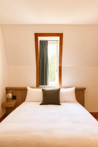 a bedroom with a white bed with a window at Hôtel Château Cran Chaud in Saguenay