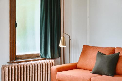 a living room with an orange couch and a window at Hôtel Château Cran Chaud in Saguenay