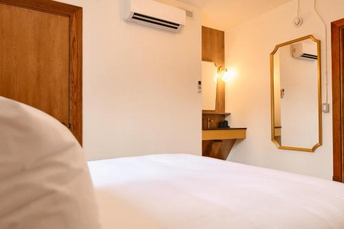 a bedroom with a white bed and a mirror at Hôtel Château Cran Chaud in Saguenay