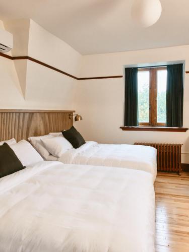 two white beds in a room with a window at Hôtel Château Cran Chaud in Saguenay