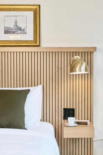 a bedroom with a bed and a table with a lamp at Hôtel Château Cran Chaud in Saguenay