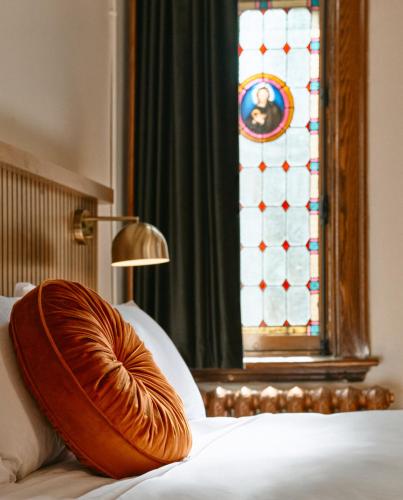 a bed with a pillow on it with a stained glass window at Hôtel Château Cran Chaud in Saguenay
