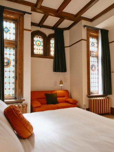 a bedroom with a bed and a couch and stained glass windows at Hôtel Château Cran Chaud in Saguenay