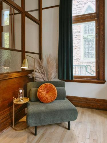 a living room with a chair with an orange pillow on it at Hôtel Château Cran Chaud in Saguenay