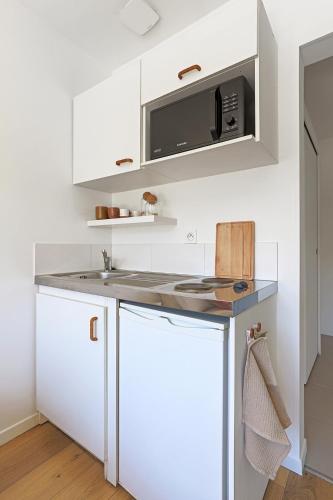 a kitchen with white cabinets and a microwave at Le studio de Gargantua in Dardilly