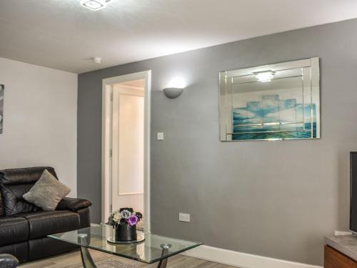 Una sala de estar con un sofá y una mesa de cristal. en Belger Cottage, en Inverallochy