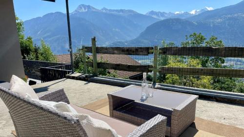 a patio with a table and chairs and mountains at La Forge de Diogne - luxury B&B and apartments in Crans-Montana