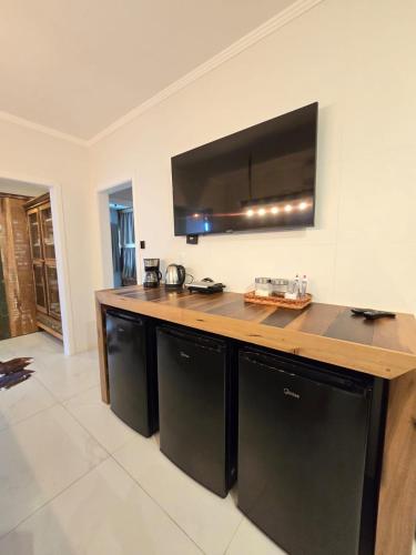 a kitchen with a counter with a television on the wall at Navega Hostel in Navegantes