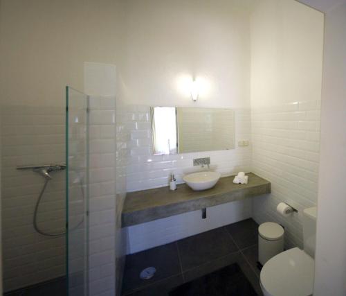 a bathroom with a sink and a shower and a toilet at Moinhos das Marés in Fuzeta