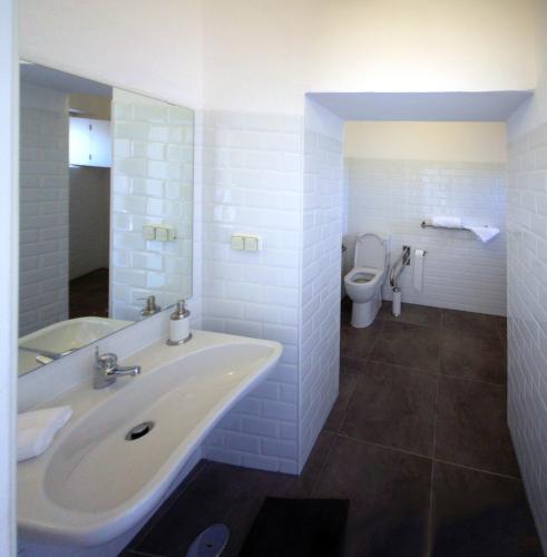 a white bathroom with a sink and a toilet at Moinhos das Marés in Fuzeta
