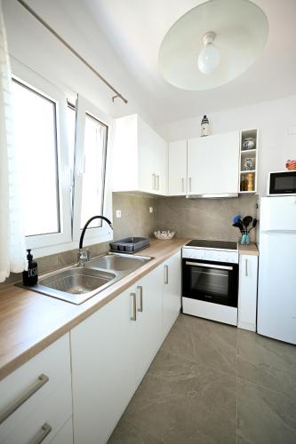 a kitchen with white cabinets and a sink at Anchor Villa in Troulos