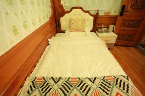 a bed with a wooden headboard in a bedroom at 梵雅民宿Vanya in Kashgar