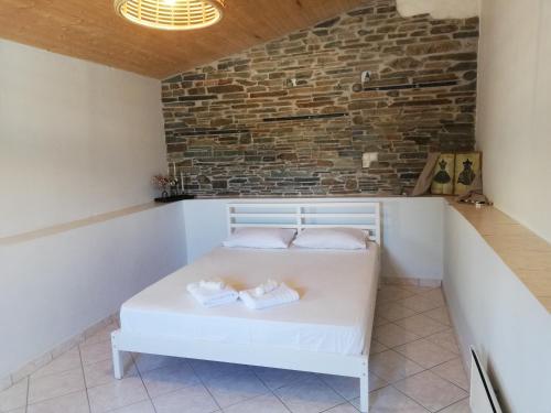 a white bed in a room with a brick wall at SPYROS STONE house in Preveza
