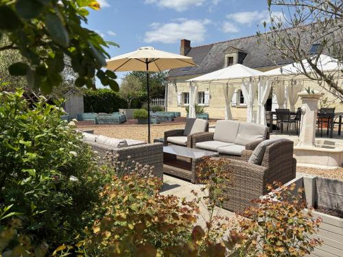 a patio with two couches and an umbrella at Les Peupliers Loire in Varennes-sur-Loire