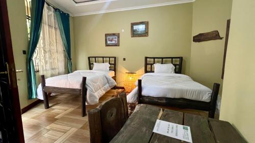 a room with two beds and a table in it at Skill forest lodge in Arusha