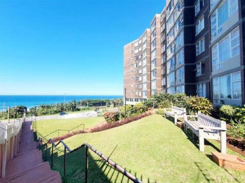 a balcony with a bench and a building and the ocean at Scottburgh Views - Piece of Paradise in Scottburgh