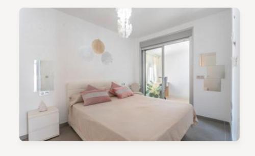 a white bedroom with a large bed with pink pillows at Divino en playa in Granadilla de Abona