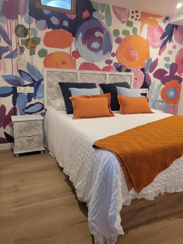 a bedroom with a bed with orange pillows and a colorful wall at Llanesmar in Posada de Llanes