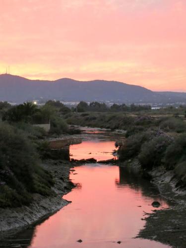 a river with a sunset in the background at Moinhos das Marés in Fuzeta