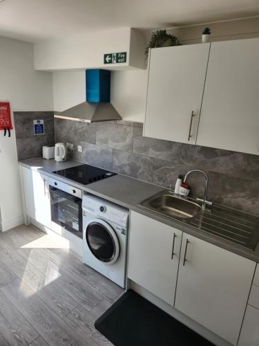 a kitchen with a washing machine and a sink at Luxurious ensuite rooms in Basildon
