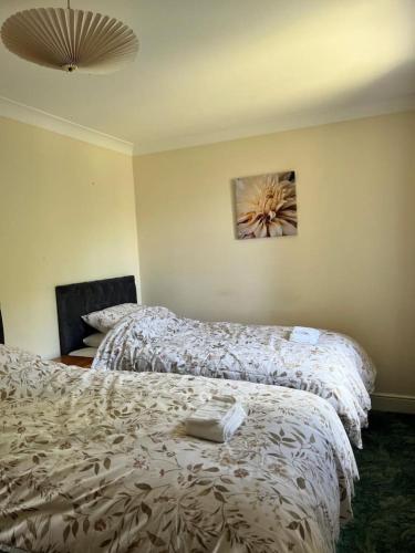 a bedroom with two beds and a painting on the wall at Canal Way- Cozy 3-Bed House in Ilminster