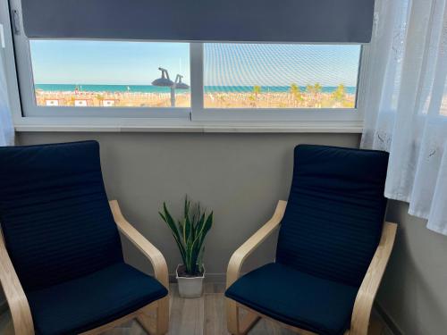 two chairs in a room with a view of the beach at Vista Mare Luxury Rooms & Apartments in Margherita di Savoia