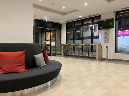 a lobby with a black couch with red pillows at Smile Hotel Hiroshima in Hiroshima
