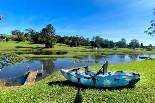 a blue boat sitting on the grass next to a lake at Oleander Escape Lake Front Retreat in Yungaburra