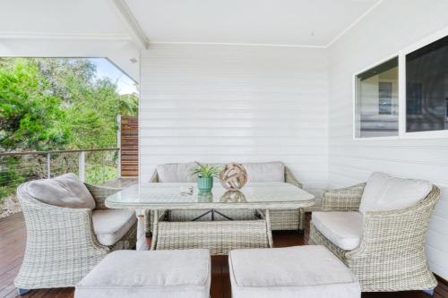 a patio with a table and wicker chairs at Oleander Escape Lake Front Retreat in Yungaburra