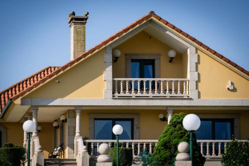 a yellow house with a balcony on it at Villa Pérez Rey in Dumbría
