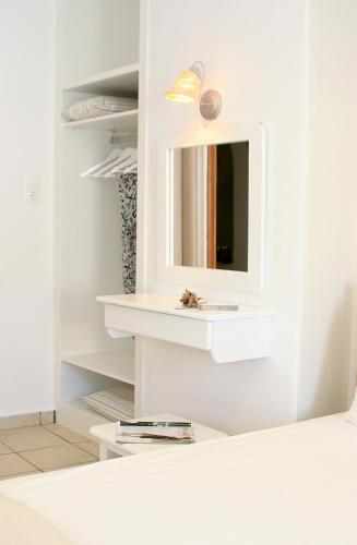 a white room with a mirror and a shelf at Paradissos Hotel in Pera Gyalos
