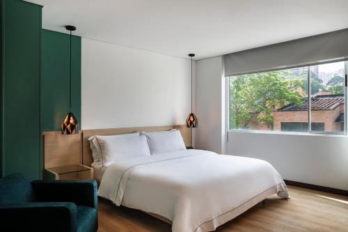 a bedroom with a white bed and a large window at Hotel Poblado Alejandria in Medellín