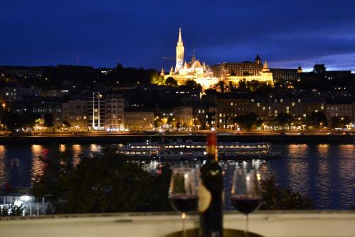 a view of a city at night with two wine glasses at Apartment Castle View in Budapest
