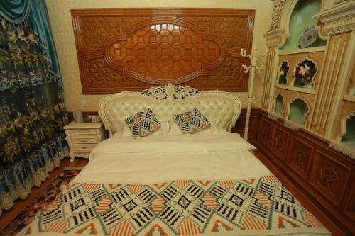 a bedroom with a white bed with a large headboard at 梵雅民宿Vanya in Kashgar