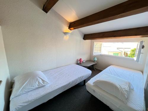une chambre avec deux lits et une fenêtre dans l'établissement Maison T3 cabine 4 couchages, terrasse cloturée, résidence Sun village avec piscine commune, 300m de la plage à PORTIRAGNES -LRSUNP5, à Portiragnes