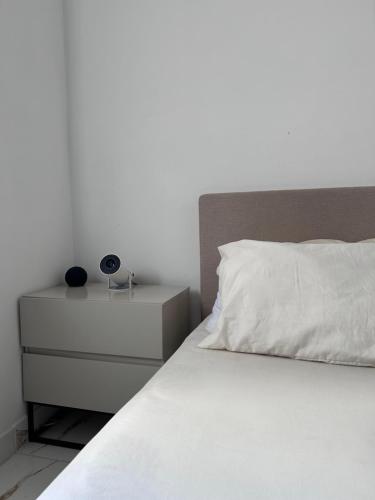 a white bed with a nightstand and a white pillow at Quarto deluxe in Sao Paulo