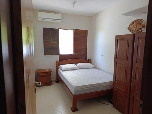 a small bedroom with a bed and a window at Praia, piscina e churrasco in Itamaracá
