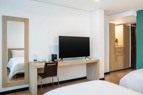 a bedroom with a desk with a television and a bed at Hotel Poblado Alejandria in Medellín