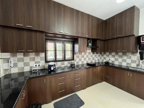 a large kitchen with wooden cabinets and a window at Naidu Nivasam in Secunderabad