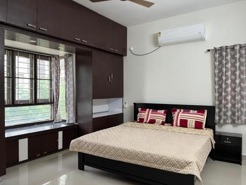 a bedroom with a bed with red pillows and a window at Naidu Nivasam in Secunderabad