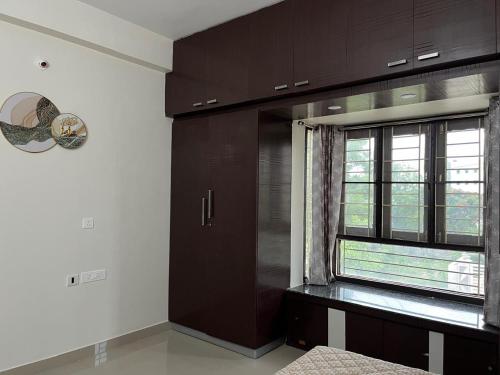 a kitchen with brown cabinets and a window at Naidu Nivasam in Secunderabad