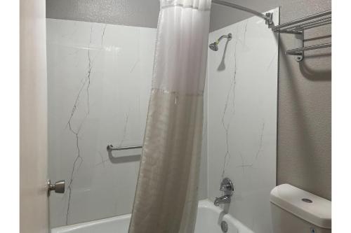 a bathroom with a shower curtain and a toilet at Studio 6 Lake Jackson, TX in Lake Jackson