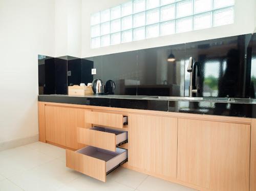 a kitchen with a black counter top and wooden cabinets at Aspen bali nusa dua in Nusa Dua