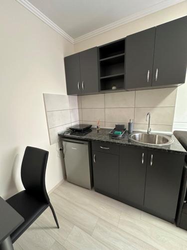 a kitchen with black cabinets and a sink at Sobe Tanja in Subotica