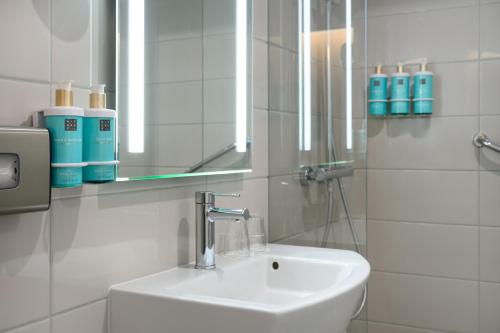 a white bathroom with a sink and a mirror at Novotel Szeged in Szeged