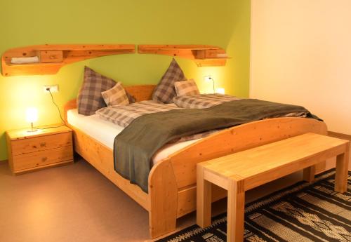 a bedroom with a large wooden bed with a bench at Ferienwohnungen Im Löwengründle in Unterkirnach